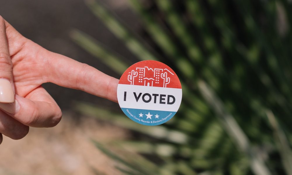 finger holding an "I Voted" sticker