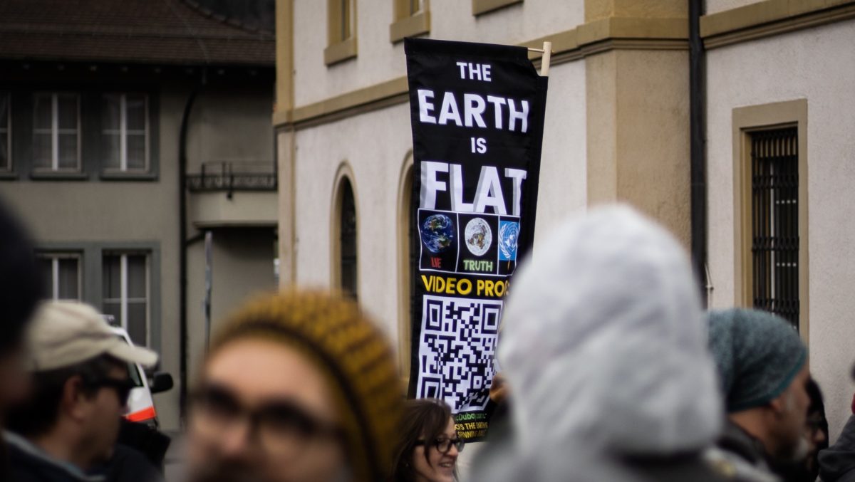 Earth is flat sign amidst protestors